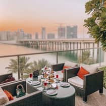 Patio armchairs and small table with dessert platter, cocktails on balcony