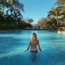 Guest enjoying a swim in the pool surrounded by lush palm trees