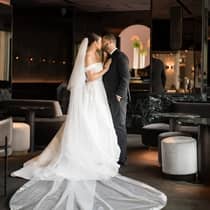 A bride and groom dressed in wedding attire share a kiss with a luxurious backdrop, a perfect moment of joy and elegance