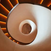 looking down into the center of a spiraling staircase with a smooth white exterior