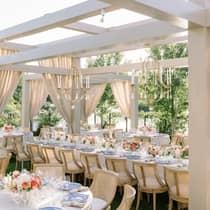 Elegant wedding reception featuring tables set beneath hanging flowers and chandeliers, creating a romantic atmosphere.