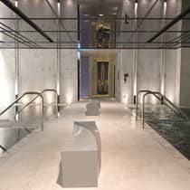 Modern white benches on tile floor between ladders leading to indoor pools, whirlpool