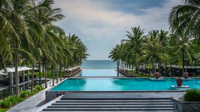Stone stairs to outdoor infinity swimming pools, palms at Four Seasons The Nam Hai Resort