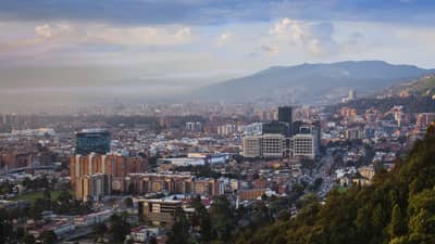Aerial view of Bogota city, buildings and houses below misty mountains