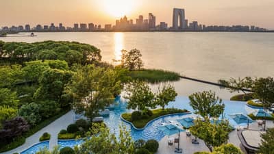 Exterior aerial shot of Four Seasons Hotel Suzhou pool grounds, with Jinji Lake and city centre in the distance