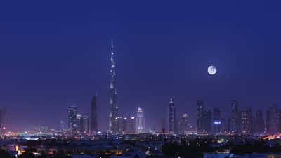 The Dubai skyline as illuminated by a full moon.