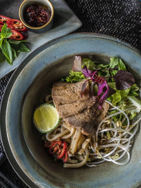 Wagyu Beef Tomahawk on noodles with green lettuce, lime