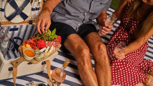 Two guests having an outdoor picnic with a charcuterie board