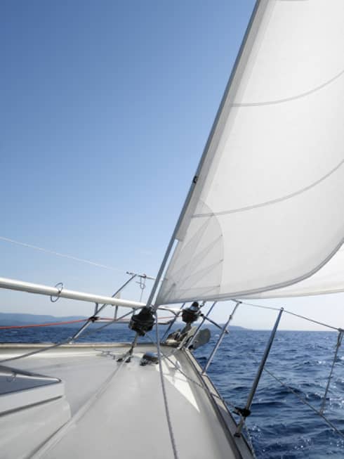 Close-up of white sails on yacht, blue ocean in background