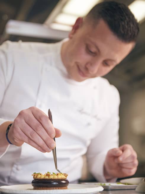 Pastry Chef Lyece Major in white chef?s coat, placing a garnish on a tart with tweezers