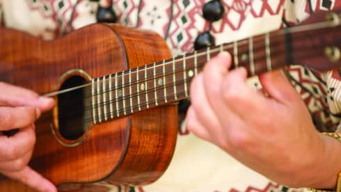 Close up of person playing ukulele instrument