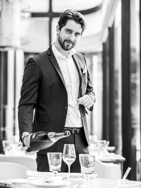 A smiling Head Sommelier Francesco Cosci pours Champagne into a flute