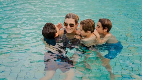 A mom and three children swim huddled together in a pool