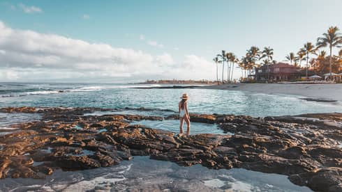 A guest exploring tidal pools by the beach in Hualalai
