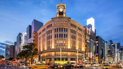 Illuminated historic building with a clock tower in a bustling city centre