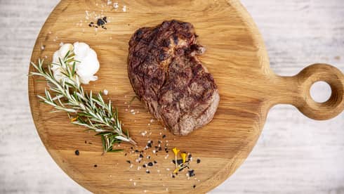 a Steak and rosemary are served on a wooden charcuterie board at fuego grill
