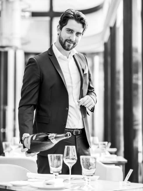 A smiling Head Sommelier Francesco Cosci pours Champagne into a flute