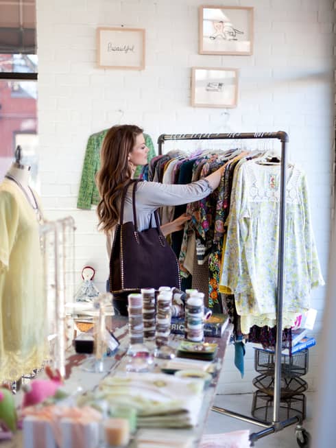 A woman looking through a rack of clothes in a store.