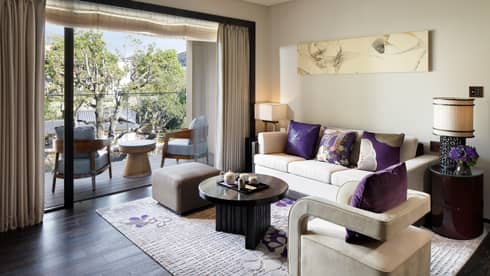 Living room sofa, armchair with plush purple pillows by open patio door, chairs