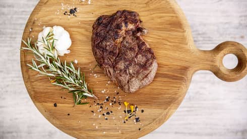 a Steak and rosemary are served on a wooden charcuterie board at fuego grill