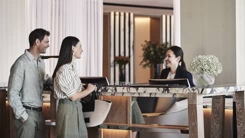 Couple checking in at hotel lobby reception desk with guest relations specialist