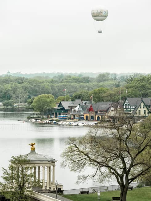 A hot air balloon in the sky near a body of water with old houses on the shore.
