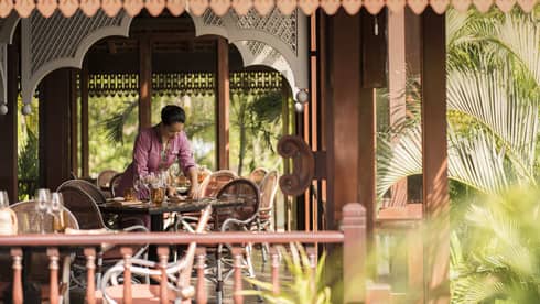 A Four Seasons staff setting the table in the open-aired Ikan Ikan at Four Seasons Langkawi