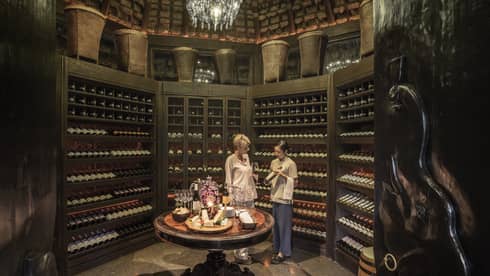 Two people examine wine bottles in Camp Wine Cellar