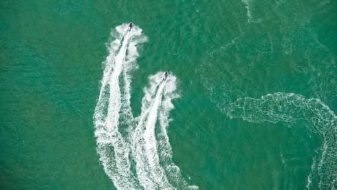 Aerial view of two jet skis, trails on water in ocean