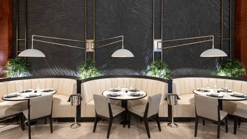 Three round dining tables next to each other surrounded by a curved booth and two chairs each.