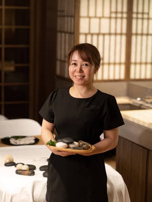 Stone therapist Sayaka Marumine poses with a tray of stones in the Spa