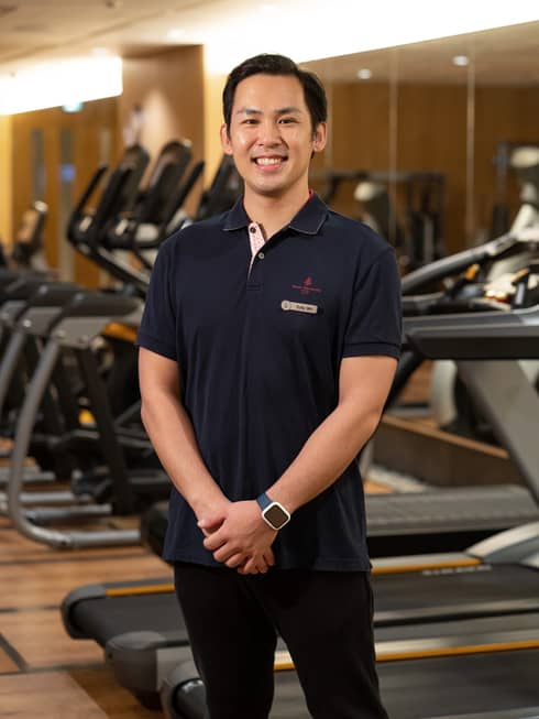 Resident Trainer Sota Sasauchi poses in front of the treadmills in the fitness centre