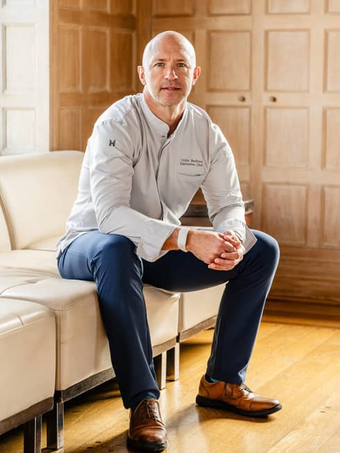 Chef Colin Bedford poses for photo on a beige leather sofa