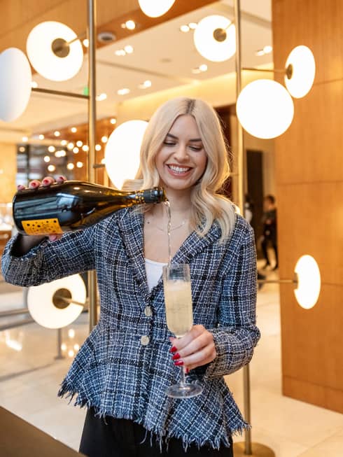 Erika Padilla wearing a black and white top and pouring a drink into a wine glass.