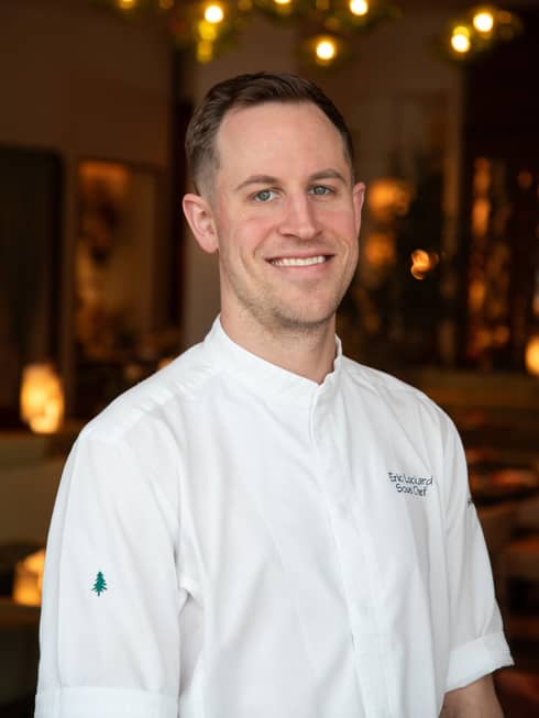 A smiling chef in a short-sleeved white shirt