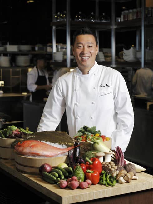 Chef Akira Back with some ingredients laid out on a cutting board