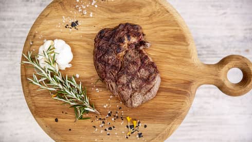 a Steak and rosemary are served on a wooden charcuterie board at fuego grill
