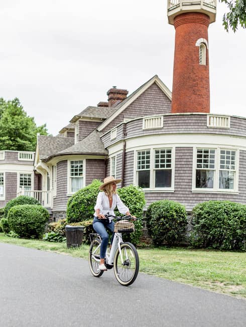 A woman riding a bicycle near an old building.