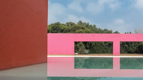 A pink building next to water outside.