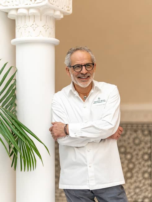 Chef Sebastiano leans about a pillar with a chef's jacket on