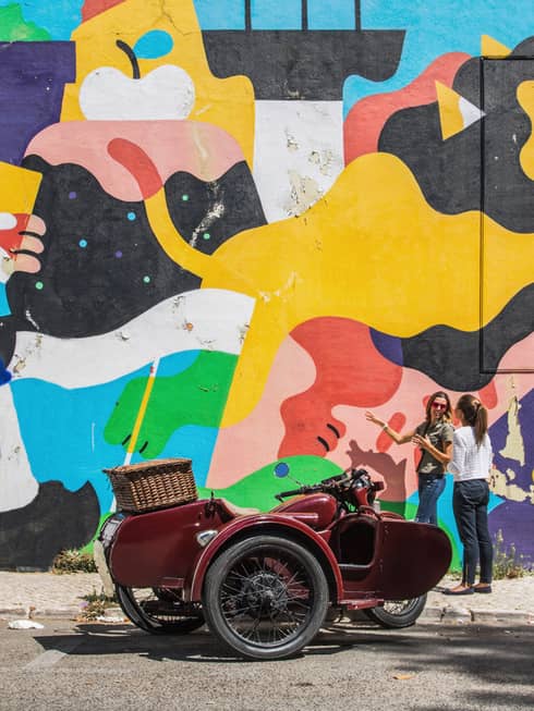 Two women stand in front of an outdoor art mural in lisbon portugual
