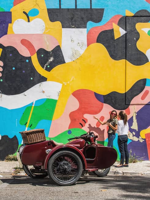 Two women stand in front of an outdoor art mural in lisbon portugual