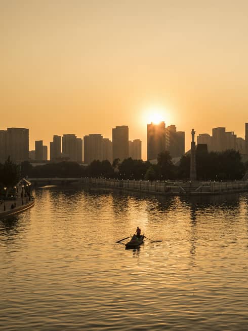 Silhouette of people in rowboat under Tianjin skyline, Eye ferris wheel at sunset