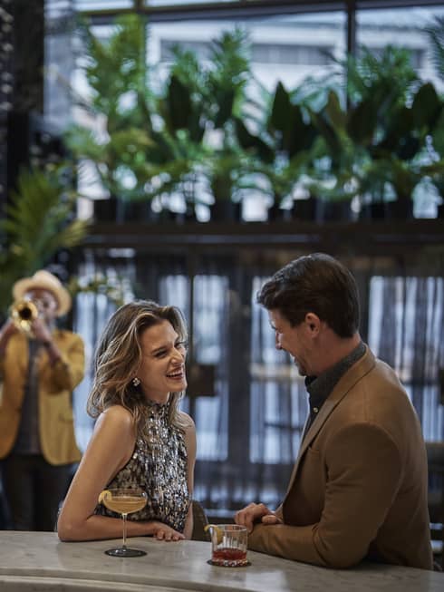 Two guests sitting at a dining table with musicians playing music in the background.