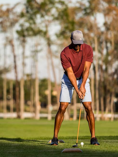A man lines up a putt in the foreground while his wife and another couple laugh in the background at the golf course at four seasons orlando