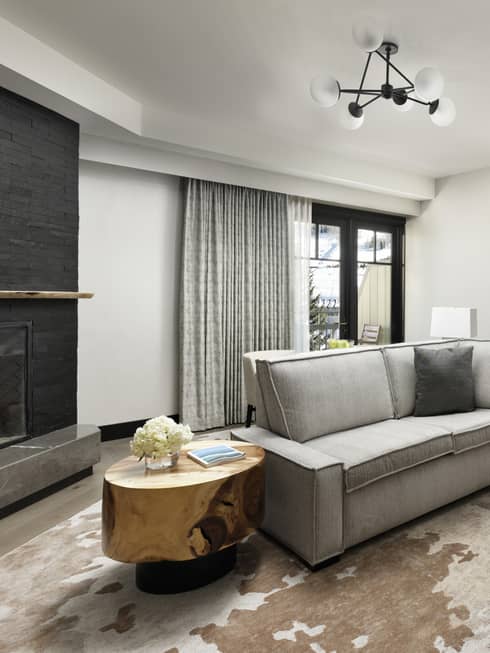Living room with small grey sofa, arm chair and ottoman, wooden side table