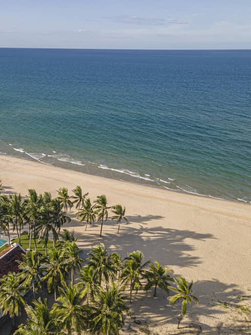 5 Bedroom Beachfront Pool Villa aerial shot with ocean and mountain views, palm trees and blue skies