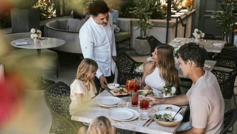 Family of four dines at a table on a restaurant terrace