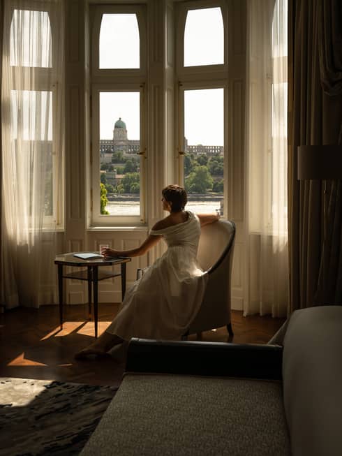 A woman looks out windows of luxury suite
