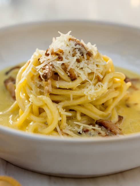 Eggs and noodles in a bowl with a yellow napkin beside it.